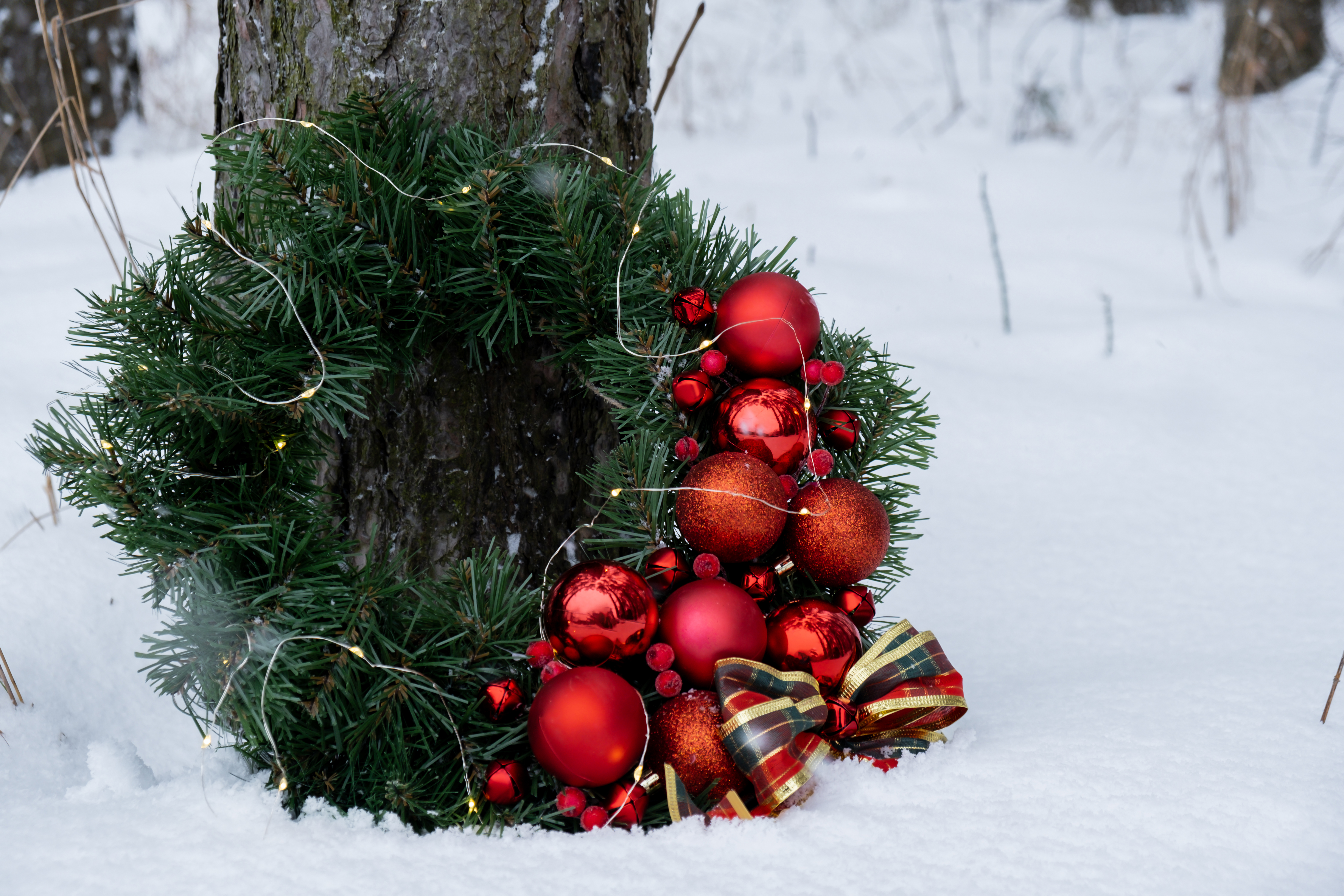Julekrans med kugler, lys og sløjfe i sne