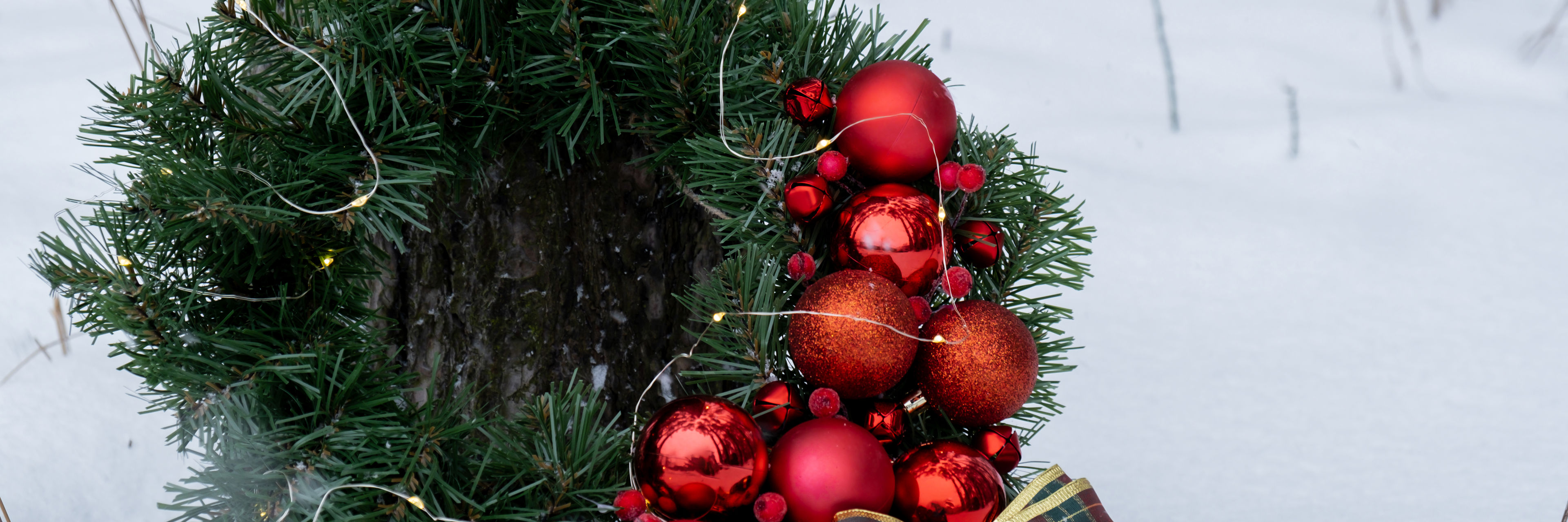 Julekrans med kugler, lys og sløjfe i sne